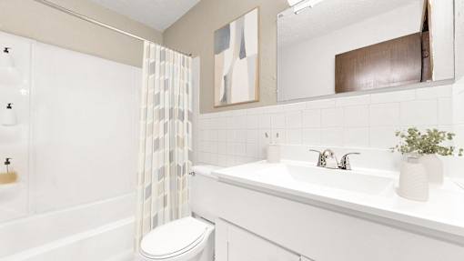 A white bathroom with a toilet, sink, and shower.
