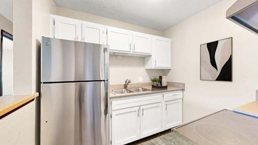 A kitchen with white cabinets and a stainless steel refrigerator.