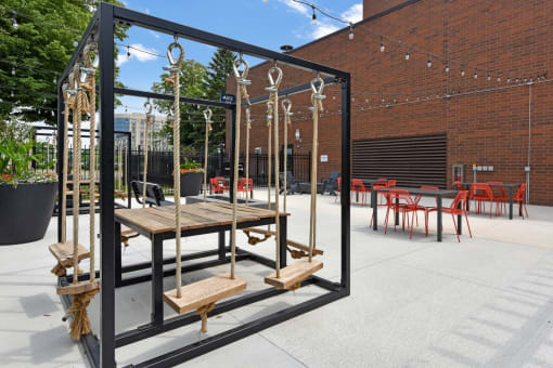 a large wooden table and chairs in a courtyard with a brick building in the background