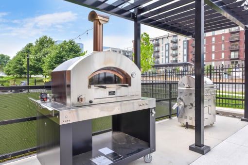 a pizza oven on a patio with a grill in the background