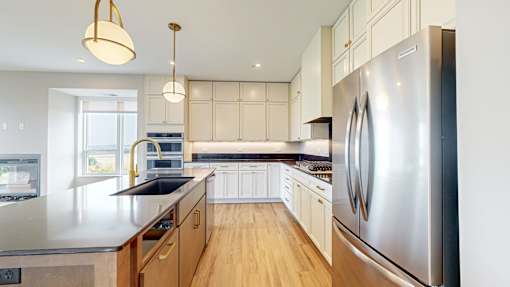 a large kitchen with stainless steel appliances and white cabinets at Ardor on the Bluffs South Loop Residences Apartments, Bloomington, Minnesota