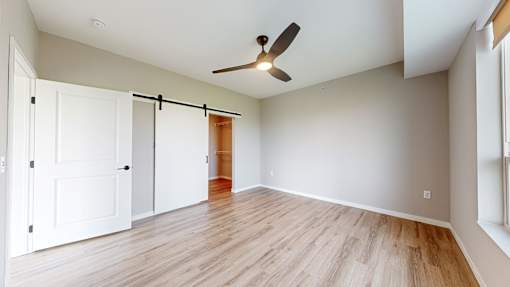 an empty living room with a ceiling fan and a closet at Ardor on the Bluffs South Loop Residences Apartments, Minnesota