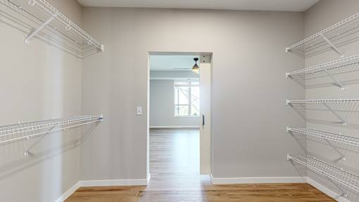 a walk in closet in a home with white walls and a door to a room at Ardor on the Bluffs South Loop Residences Apartments, Minnesota