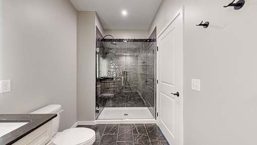a bathroom with a shower and a toilet and a sink at Ardor on the Bluffs South Loop Residences Apartments, Bloomington