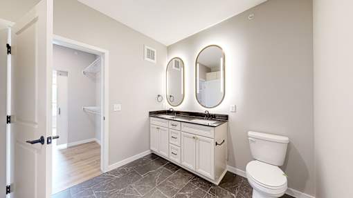 a white bathroom with a toilet and a sink at Ardor on the Bluffs South Loop Residences Apartments, Bloomington