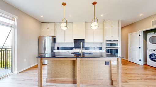 a kitchen with white cabinets and a counter top with a sink at Ardor on the Bluffs South Loop Residences Apartments, Minnesota