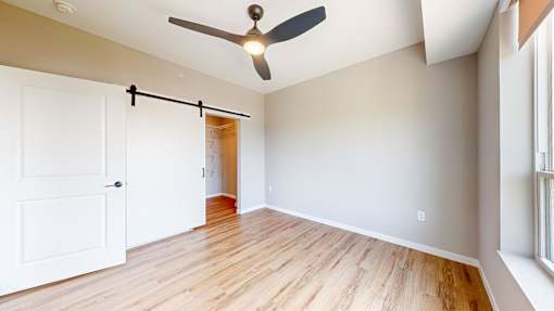 an empty living room with a ceiling fan and a door to a closet at Ardor on the Bluffs South Loop Residences Apartments, Bloomington, 55425