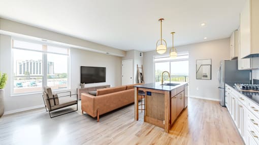 an open living room with a kitchen and a tv at Ardor on the Bluffs South Loop Residences Apartments, Minnesota