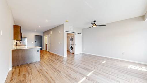 an empty living room with a kitchen and a washer and dryer at Ardor on the Bluffs South Loop Residences Apartments, Minnesota