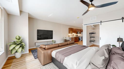a bedroom with a couch and a tv at Ardor on the Bluffs South Loop Residences Apartments, Bloomington