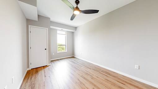 an empty living room with wood floors and a ceiling fan at Ardor on the Bluffs South Loop Residences Apartments, Bloomington, Minnesota