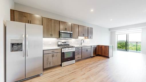a kitchen with stainless steel appliances and wooden cabinets at Ardor on the Bluffs South Loop Residences Apartments, Bloomington, MN