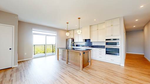 A kitchen with a wooden floor and white walls.