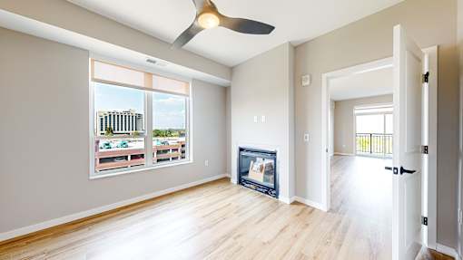 A room with a ceiling fan and a large window overlooking a cityscape.