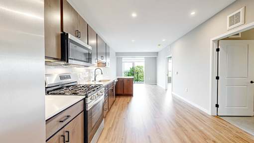 A modern kitchen with wooden floors and stainless steel appliances.