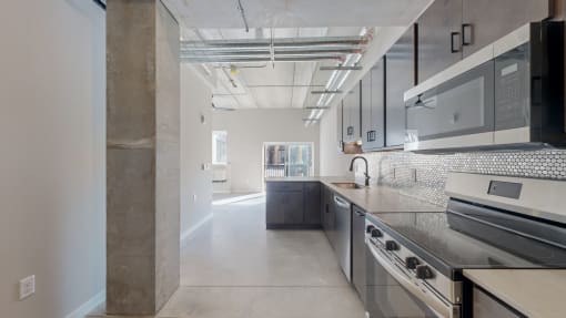 A modern kitchen with stainless steel appliances and a large island at Ardor on the Bluffs South Loop Residences Apartments, Bloomington, MN, 55425