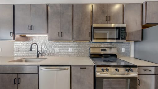 an empty kitchen with stainless steel appliances and cabinets at Ardor on the Bluffs South Loop Residences Apartments, Bloomington, MN
