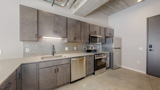 a kitchen with stainless steel appliances and a sink and a refrigerator at Ardor on the Bluffs South Loop Residences Apartments, Minnesota