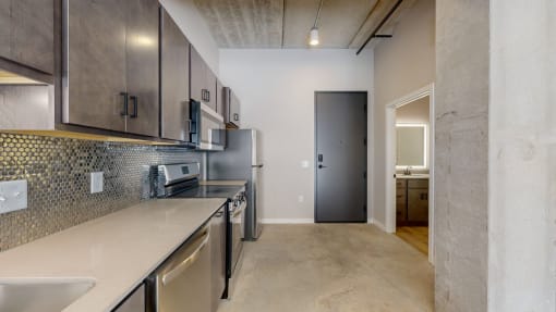 a renovated kitchen with stainless steel appliances and a door to a hallway at Ardor on the Bluffs South Loop Residences Apartments, Bloomington, 55425