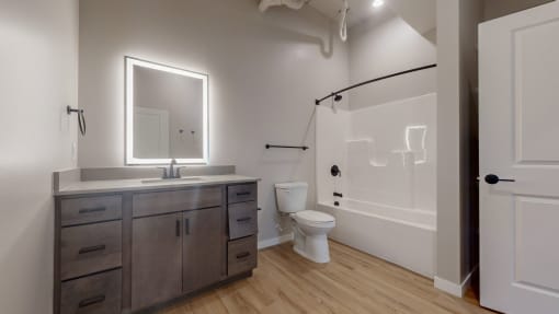 a bathroom with a toilet sink and shower and a mirror at Ardor on the Bluffs South Loop Residences Apartments, Bloomington, MN