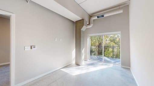 an empty living room with a sliding glass door to a balcony at Ardor on the Bluffs South Loop Residences Apartments, Minnesota
