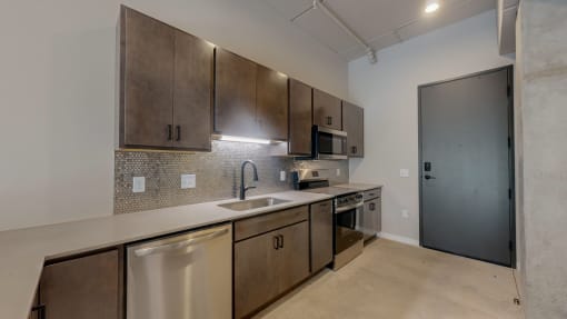 an empty kitchen with stainless steel appliances and wooden cabinets at Ardor on the Bluffs South Loop Residences Apartments, Bloomington, Minnesota