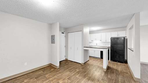 A kitchen area with a black fridge and white cabinets.