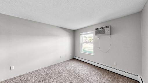 A room with a window and a carpeted floor.