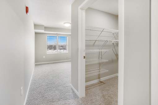 A white room with a window and a white closet.