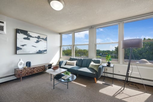 the living room of an apartment with a blue couch and a large window