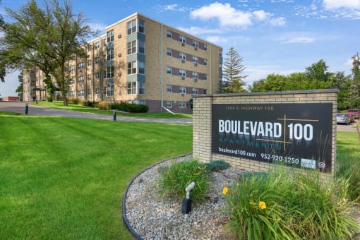 a sign for the boulevard 100 apartment complex in front of a green grass field