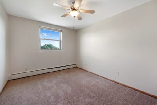 an empty room with a ceiling fan and a window