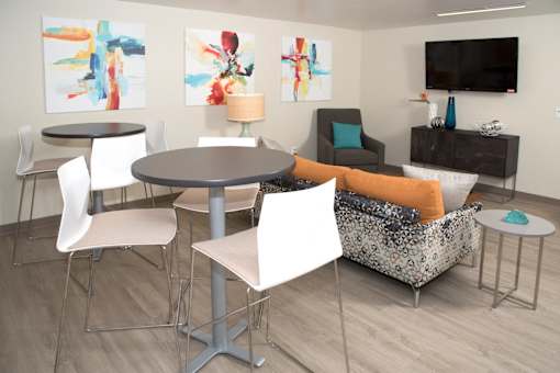 A laundry lounge with a grey table surrounded by white chairs.