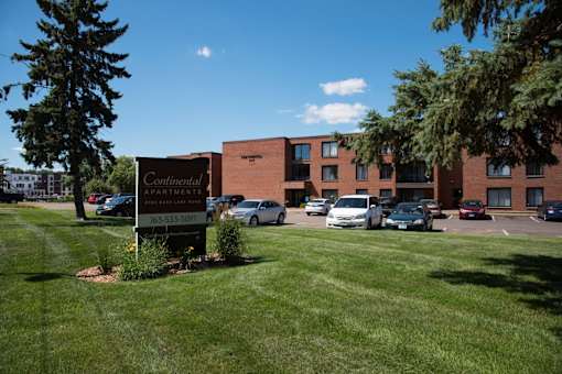 A parking lot with cars and a sign for Continental Apartments.