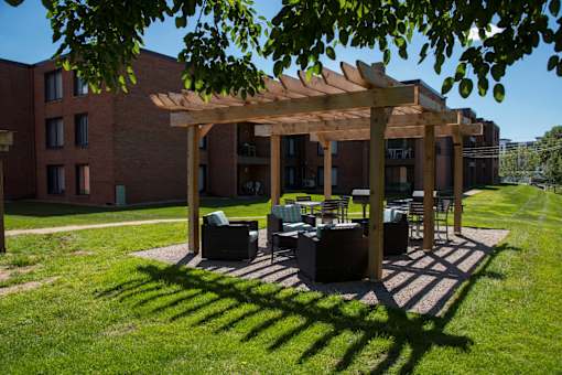 A wooden pergola is over a set of outdoor furniture.