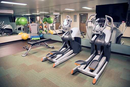 A gym with exercise equipment and a mirror.