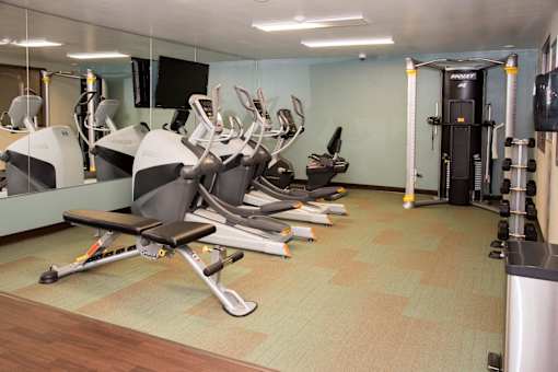 A gym with a variety of equipment including treadmills, weights, and exercise machines.
