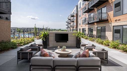 A patio with grey couches and a fireplace.