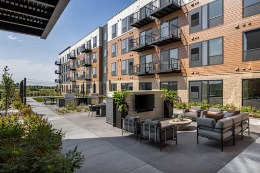 A modern outdoor seating area is surrounded by contemporary apartment buildings.