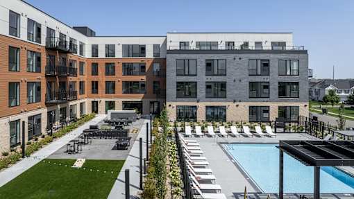A modern building with a pool and lounge chairs.