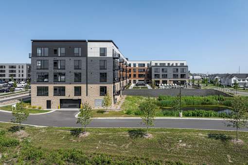 A modern building complex with a parking lot in front.