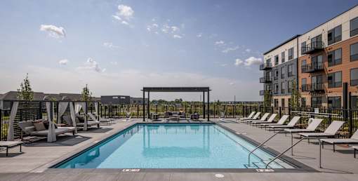 A swimming pool surrounded by lounge chairs and umbrellas.