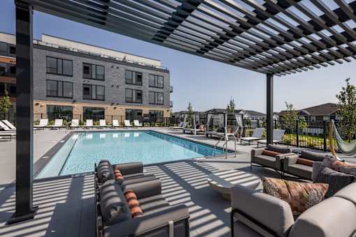 A pool area with sun loungers and a building in the background.