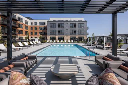 A pool surrounded by lounge chairs and umbrellas.