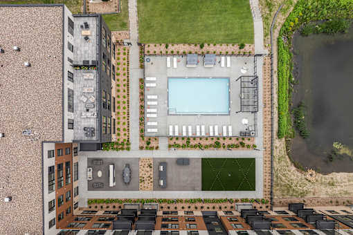 A bird's eye view of a building with a pool and parking lot.