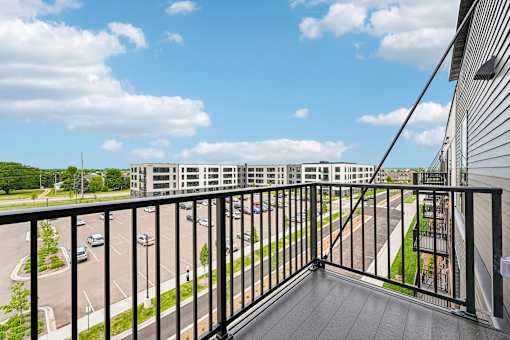 A balcony overlooks a parking lot and a road.