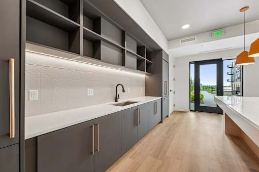 A modern kitchen with dark grey cabinets and a wooden floor.
