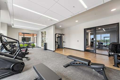 A gym with a variety of equipment including treadmills, weights, and exercise machines.