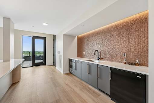 A modern kitchen with a dark brown backsplash and wooden floors.