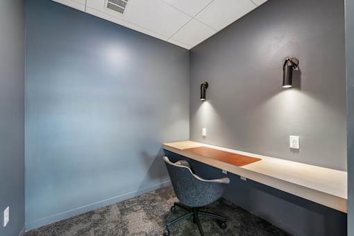 A grey chair is in front of a grey wall with a brown mat on the desk.